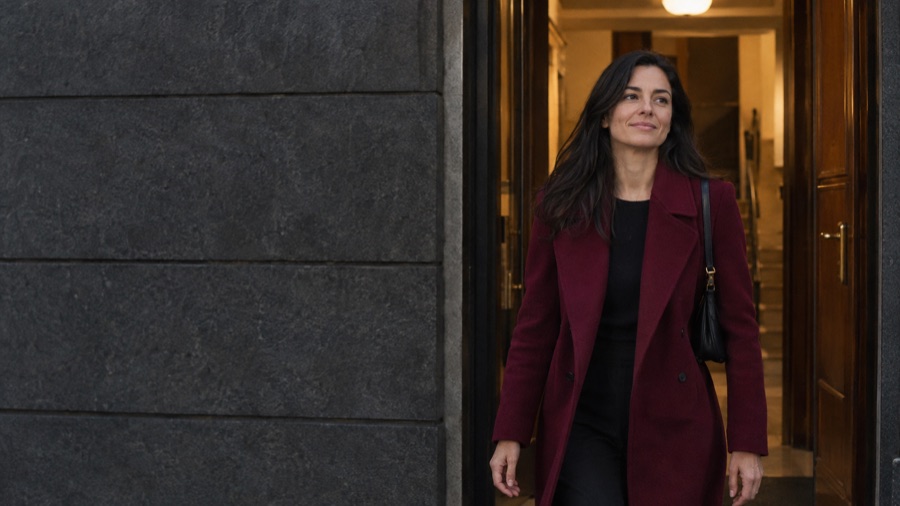 Esce dal portone a testa alta, con il cappotto bordeaux