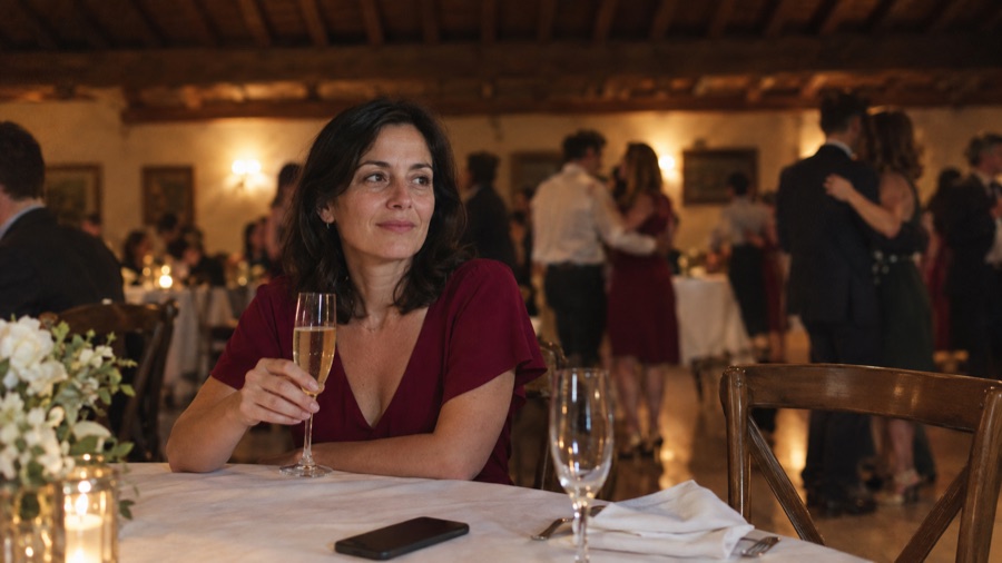 Al matrimonio, seduta da sola al tavolo, guarda le coppie che ballano